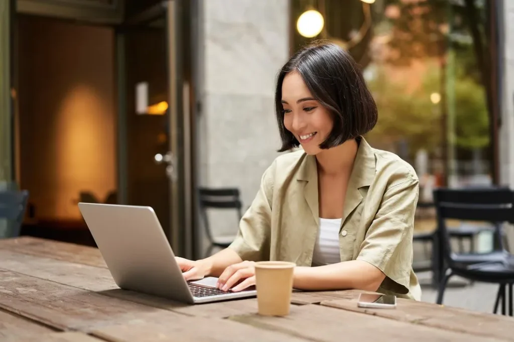 imgi 6 young asian woman digital nomad working remotely from cafe drinking coffee using laptop Vetencode